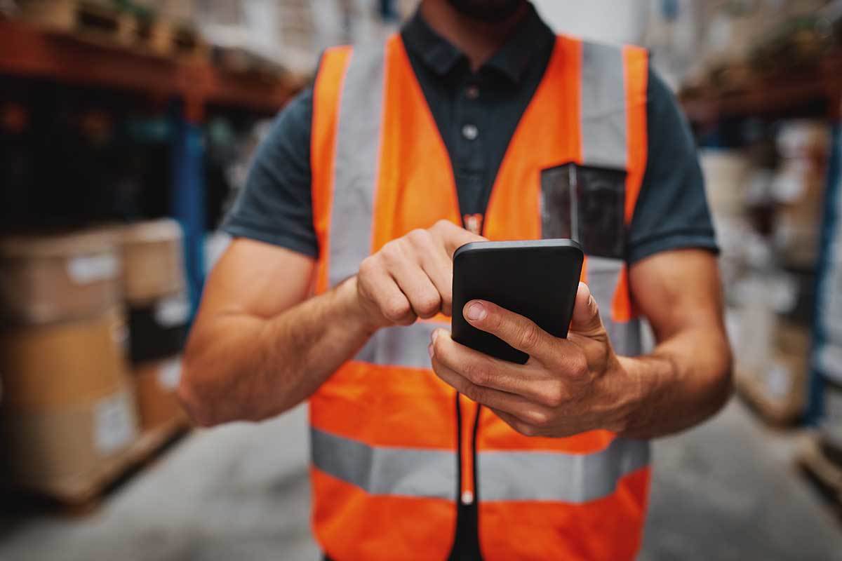 Radnik u skladištu koristi telefon Radnik u skladištu koristi telefon