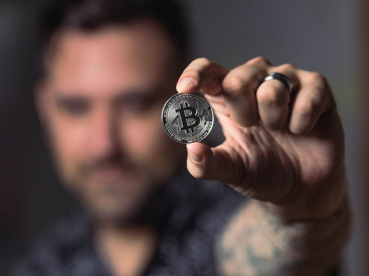  Čovek drži Bitcoin novčić u ruci 