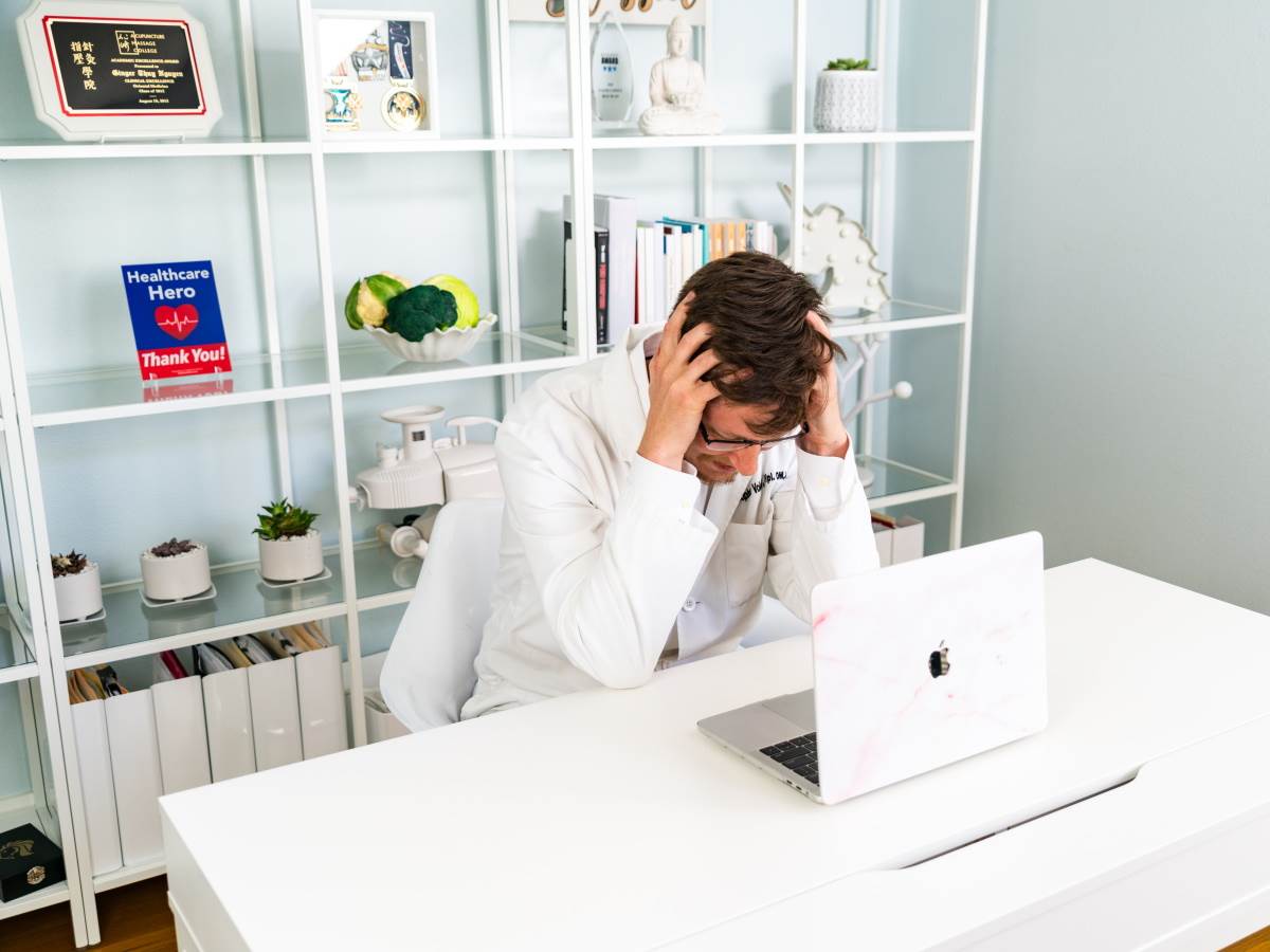 Zaposleni sedi ispred računara i drži se za glavu   Zaposleni sedi ispred računara i drži se za glavu