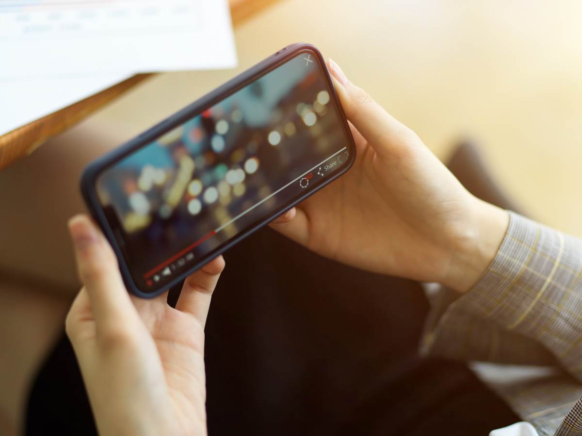 Žena drži telefon i gleda YouTube video sa zamućenom pozadinom   Žena drži telefon i gleda YouTube video sa zamućenom pozadinom