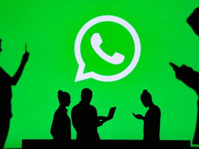 Ljudi predstavljeni kao senke koriste Whatsapp na telefonu i laptopu sa velikim Whatsapp logotipom na sredini Ljudi predstavljeni kao senke koriste Whatsapp na telefonu i laptopu sa velikim Whatsapp logotipom na sredini