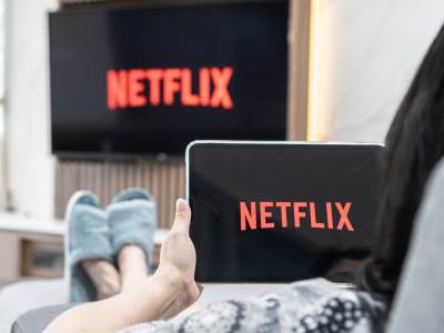 Žena gleda Netflix na tabletu i na TV-u 